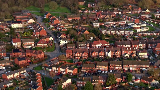 Aerial drone view of Baddesley Ensor village, featuring charming brick residential houses bathed in warm, golden light during sunset.