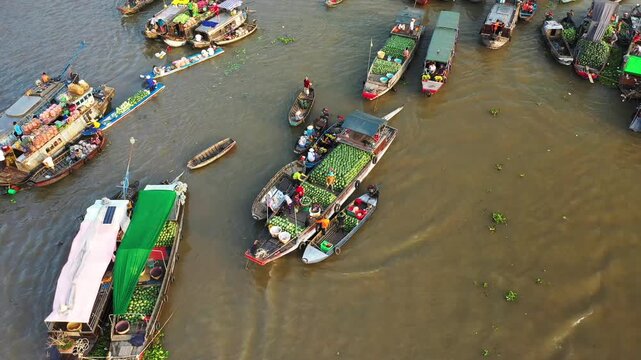 Aerial view of traditional boats trading fresh produce at the Cai Rang floating market on a river in Vietnam. Vibrant scene of local commerce and culture.