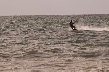 에메랄드빛 바다 위에서 시원하게 바람을 가르며 카이트 서핑을 즐기는 역동적인 해양 스포츠 풍경
