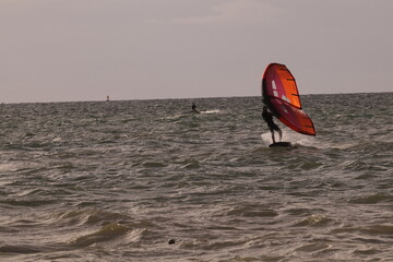에메랄드빛 바다 위에서 시원하게 바람을 가르며 카이트 서핑을 즐기는 역동적인 해양 스포츠 풍경

