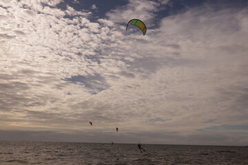 에메랄드빛 바다 위에서 시원하게 바람을 가르며 카이트 서핑을 즐기는 역동적인 해양 스포츠 풍경
