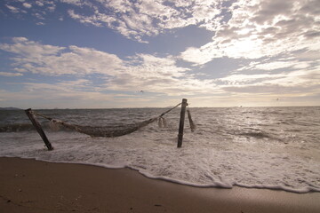 에메랄드빛 해변에 설치된 해먹 위로 밀려오는 역동적인 파도와 시원한 여름 휴양지 풍경
