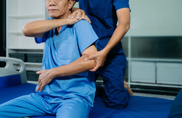 Obraz premium Physiotherapist assisting senior patient with shoulder rehabilitation in hospital clinic. Healthcare, recovery, pain relief and elderly mobility