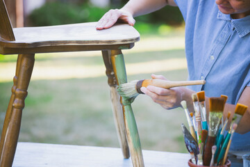 Woman  painting a wooden furniture outdoors, an eco-friendly re-use business.
