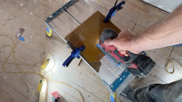 A jigsaw cuts a board. A top-down view, medium shot. A jigsaw in the hands of a craftsman. Interior renovation. Interior restoration and refurbishment. Home improvement.
