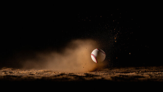 Baseball partially obscured by a rising cloud of red-brown dust after a powerful hit or slide