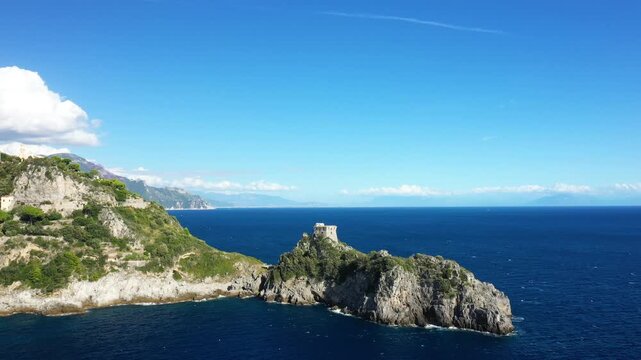 Scenic view of the Capo di Conca coastline with a historic watchtower overlooking the deep blue Mediterranean Sea under a clear sky in Italy.