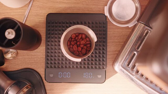 Man adding single Coffee Bean to scale to reach exact 18 gram during Espresso Preparation, Top View with Warm Light and Slow Motion emphasizing precision and portion accuracy
