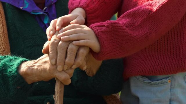 Grandparent walking and holding hands with their grandchild in nature on family trip. Old Senior woman walking while holding hands with her grandson.