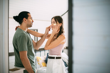 Fototapeta premium Family spa day at home. Young woman and man with golden hyaluronic patches on their faces in the bedroom of their home.
