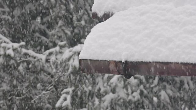 Heavy snow falling on roof gutter