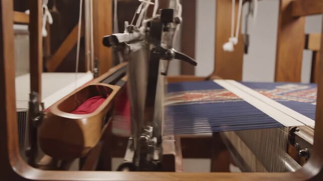 Closeup of a traditional wooden handloom weaving machine in operation showcasing intricate threads and the weaving process in detail.