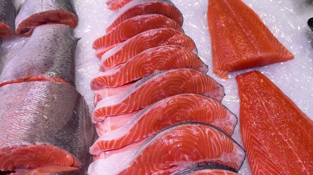 Vibrant red raw salmon fillets and steaks freshly displayed on crushed ice in a market setting