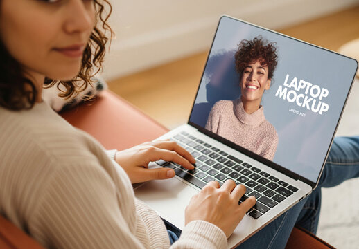 Close-up laptop mockup of woman using notebook at home on sofa, looking back