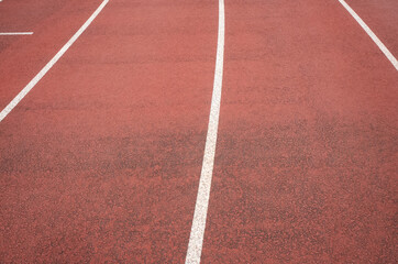 Empty red running track with white lane lines perspective