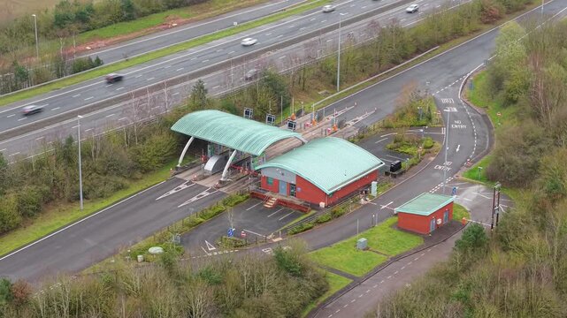 Aerial drone view of the M6 Toll motorway and its automated payment booths, with HGVs and commuter vehicles passing through near Birmingham, UK.