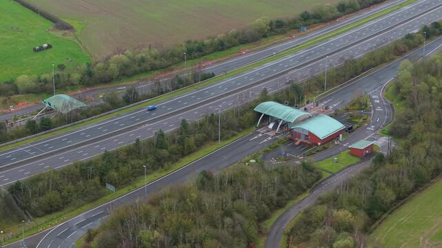 Aerial drone view of the M6 Toll motorway and its automated payment booths, with HGVs and commuter vehicles passing through near Birmingham, UK.