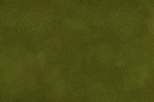 Dark green suede fabric background with matte nap velvet texture. Olive tones and soft felt textile surface in macro