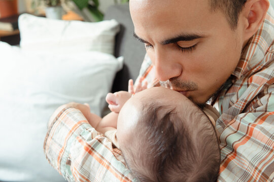 Father tenderly kissing newborn baby head showing affection
