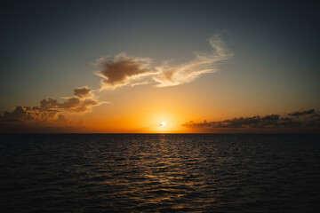 Beautiful sunset over a calm dark ocean with golden clouds