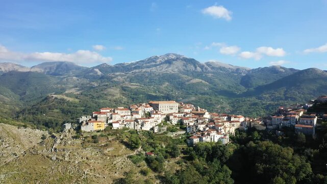 Scenic aerial view of the historic village of Aieta nestled among lush green mountains under a clear blue sky. Picturesque landscape with traditional architecture and natural surroundings.