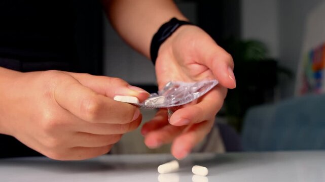 Closeup of hands pushing white tablets from a blister pack, one pill resting on a clean counter in soft light. Daily medication routines support recovery, but safe dosing and adherence matter.