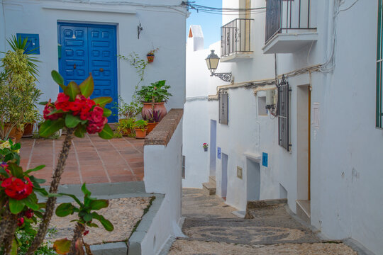 Charming narrow street with white buildings and a vibrant blue door in a Mediterranean village