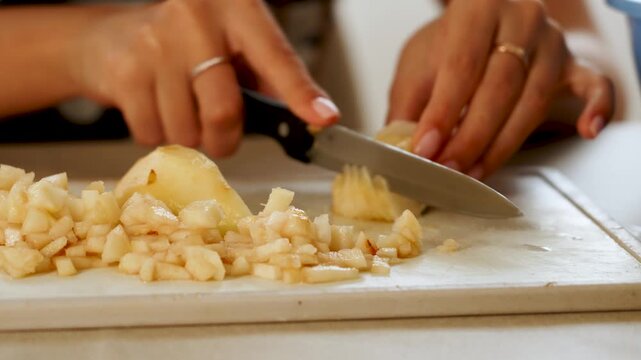 Slicing a pear on a cutting board in a kitchen during daytime