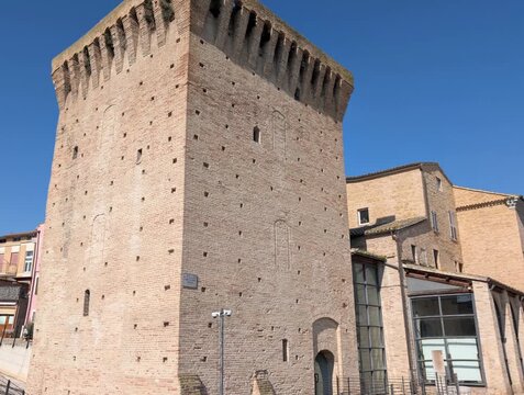 Torre storica in pietra e mattoni chiari con merlature, parte di un&rsquo;antica struttura difensiva italiana, ripresa in una giornata limpida