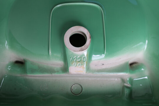 Close-up view of the underside of a vintage green ceramic sink with embossed markings