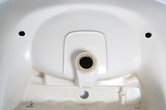 Close-up of a ceramic sink underside showing drain hole and markings