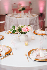 Elegant dining table setting with pink roses and gold chargers