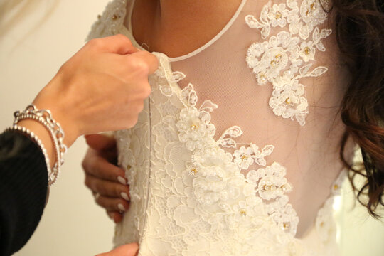Bride getting dressed with intricate lace details and delicate beadwork on her wedding gown