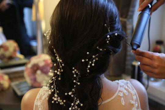 Elegant bridal hairstyle with pearls and curls in soft lighting