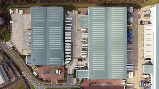 Top-down aerial drone view of a large distribution centre in Birmingham, UK, featuring rows of HGVs waiting at busy warehouse loading bays.