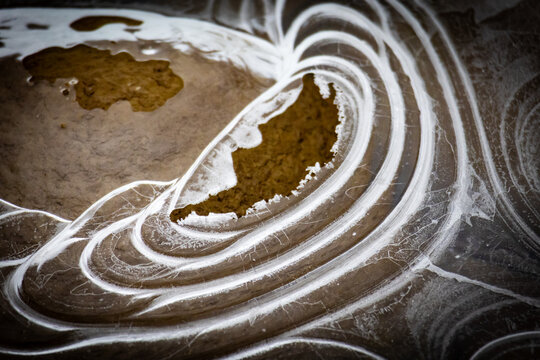 Raised island shapes sit within a shallow glaze of ice while bright rings sweep around them like tides paused in time a peaceful winter scene filled with rounded contours and gentle rhythm