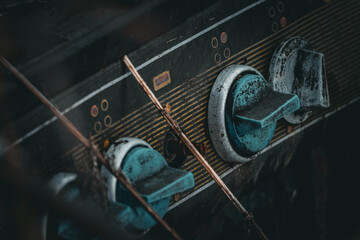 Close view of teal knobs on a stained panel reveals age and wear. The household cooker now stands silent with marks of grease and rust telling quiet stories of busy kitchens past © Oleh
