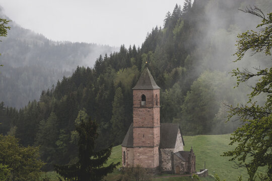 Misty view of St. Kathrein Church near Hafling (Avelengo), surrounded by alpine forest and meadow in South Tyrol, Italy
