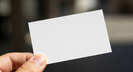 Obraz premium Person Holding a Blank Business Card, Emphasizing a Minimalistic and Professional Design in Soft Lighting
