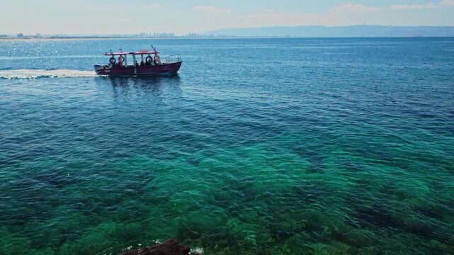Tourists exploring mediterranean sea from boat near akko shore
