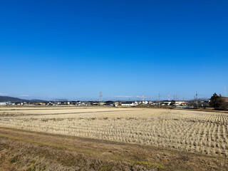 青い空と収穫後の枯れた田園