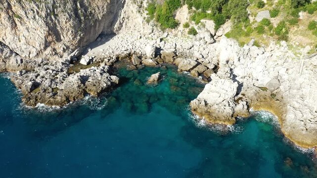 Aerial view of the rocky coastline and turquoise waters at Capo di Conca, Italy. Rugged cliffs and vibrant blue sea create a scenic Mediterranean landscape.