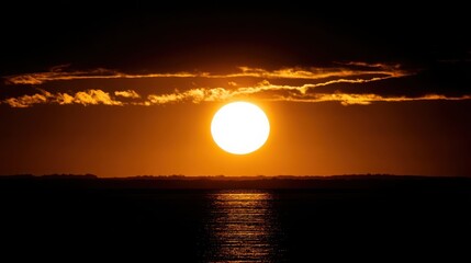 Fototapeta premium Brilliant sun setting over the ocean horizon with golden twilight colors illuminating the sky and water