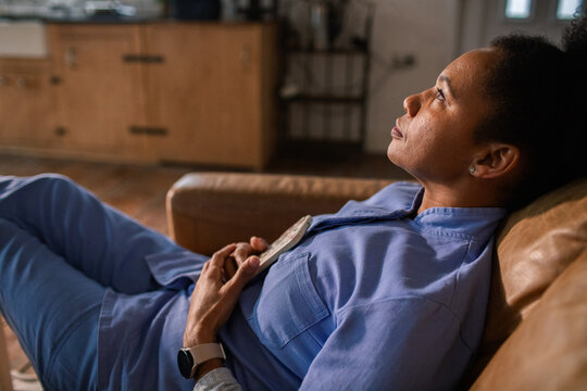 Tired healthcare worker resting on couch at home