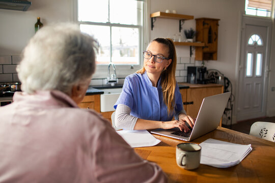 Home nurse consulting senior patient in kitchen
