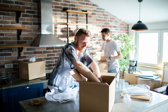 Two men packing boxes in a modern kitchen
