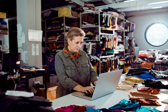 Small business owner using laptop in textile workshop