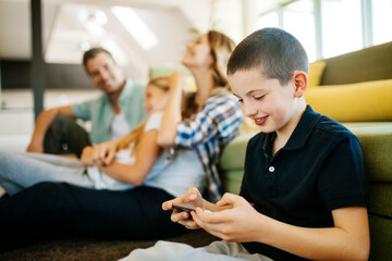 Young boy using smartphone with family in living room