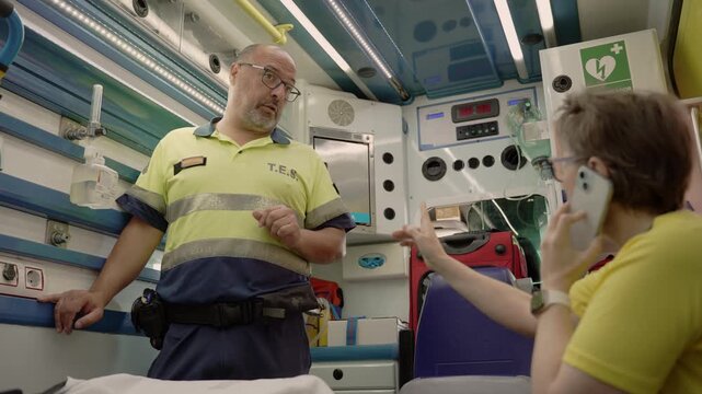 Paramedics discussing while transporting patient in ambulance