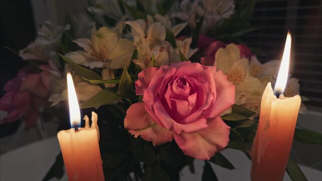 Pink rose bouquet illuminated by flickering candlelight